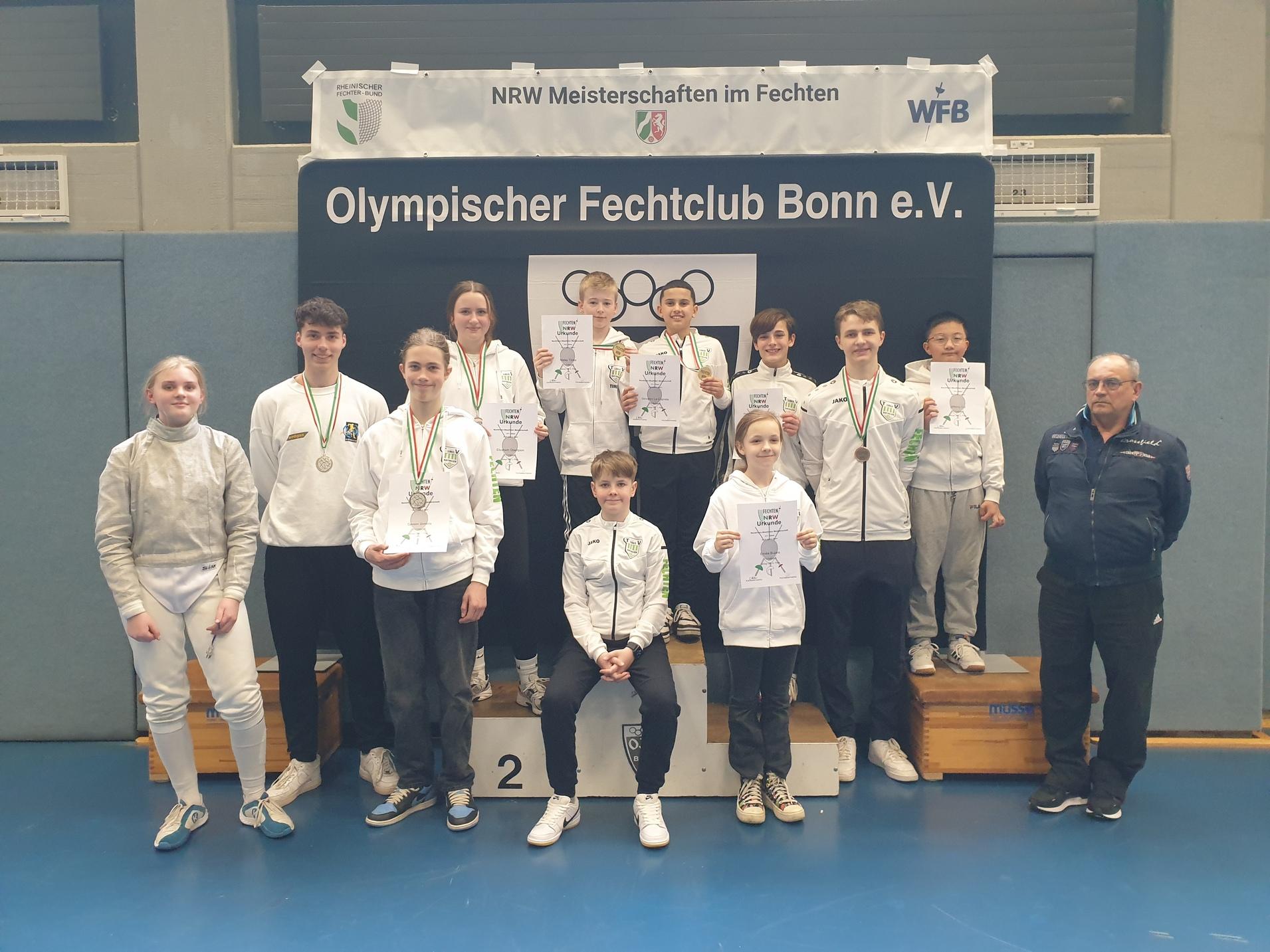 Gruppenshot von Fechtsportlern des Olympischen Fechtclubs Bonn e.V. mit Medaillen und Urkunden auf einer Siegerehrung.