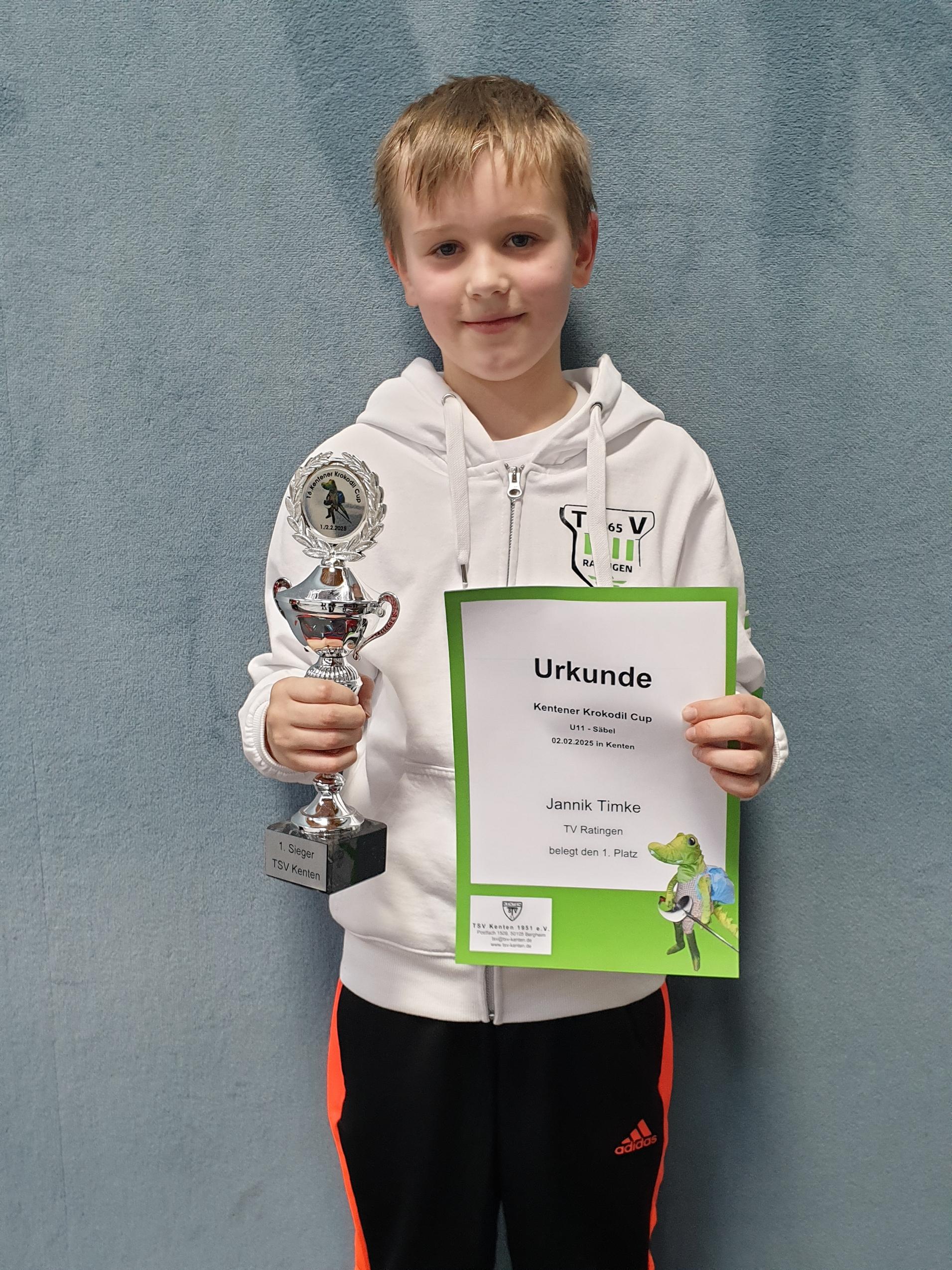 Junge hält Pokal und Teilnehmerurkunde für den ersten Platz beim Kentener Krokodil Cup in der Hand.