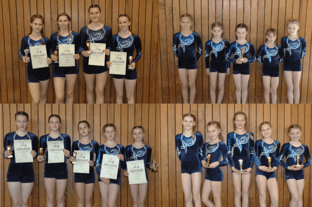 Sechs M&auml;dchen in Gymnastikanz&uuml;gen halten Pokale und Urkunden vor einer Holzwand. Zwei Gruppen in zwei Reihen.