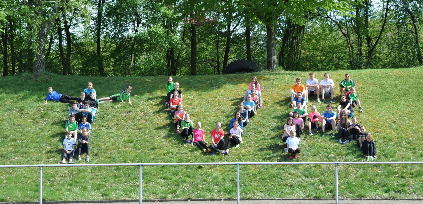Gruppenszenen von Jugendlichen in Sportkleidung auf einer gr&uuml;nen Wiese, angeordnet in der Form eines gro&szlig;en "P".