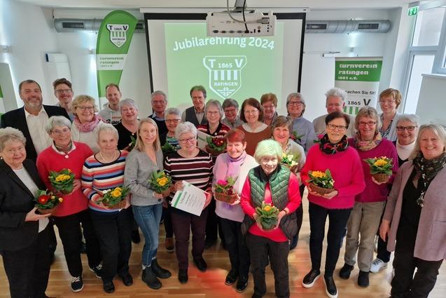 Gruppenfoto von Mitgliedern des Turnvereins Ratingen 1865 e.V. mit Blumenstr&auml;u&szlig;en in einer Feierraum.