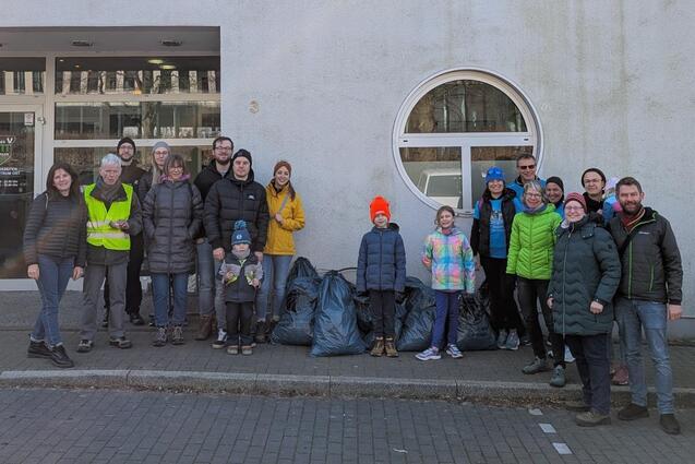 Gruppe von Personen mit M&uuml;lls&auml;cken vor dem Sportzentrum Turnverein Ratingen, im Hintergrund das Geb&auml;ude mit Schildern.