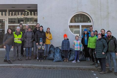 Gruppe von Personen mit M&uuml;lls&auml;cken vor dem Sportzentrum Turnverein Ratingen, im Hintergrund das Geb&auml;ude mit Schildern.