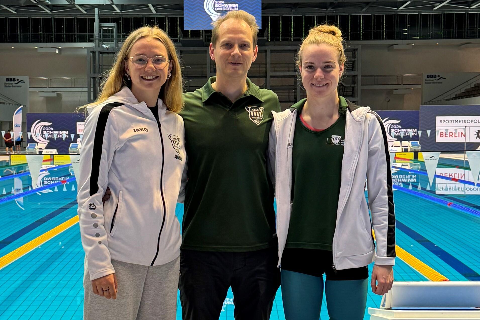 Drei Schwimmer stehen am Beckenrand eines Schwimmbades, mit blauen Wasser und Wettkampfausrüstung im Hintergrund.