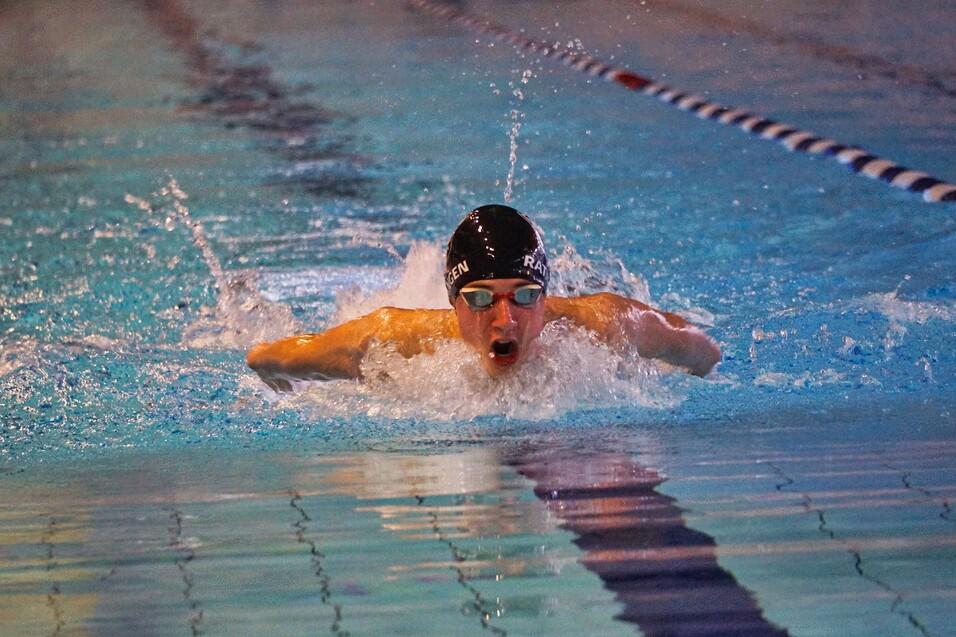 Schwimmer in Aktion beim Schmetterlingsstil, mit spritzendem Wasser im Swimmingpool.