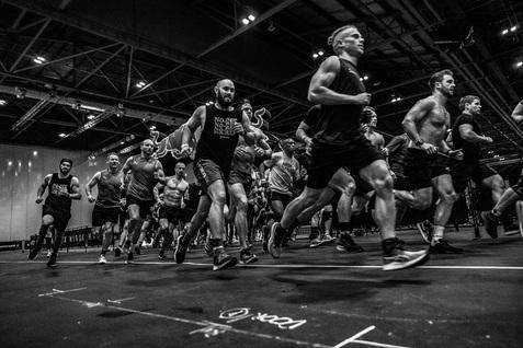 Gruppe von Sportsmännern, die in einem Wettkampf schnell über eine schwarze Fläche laufen. Event im Innenbereich.