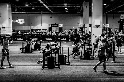 Gruppentraining in einer Fitnesshalle mit Sportlern, die an verschiedenen Stationen Übungen durchführen.