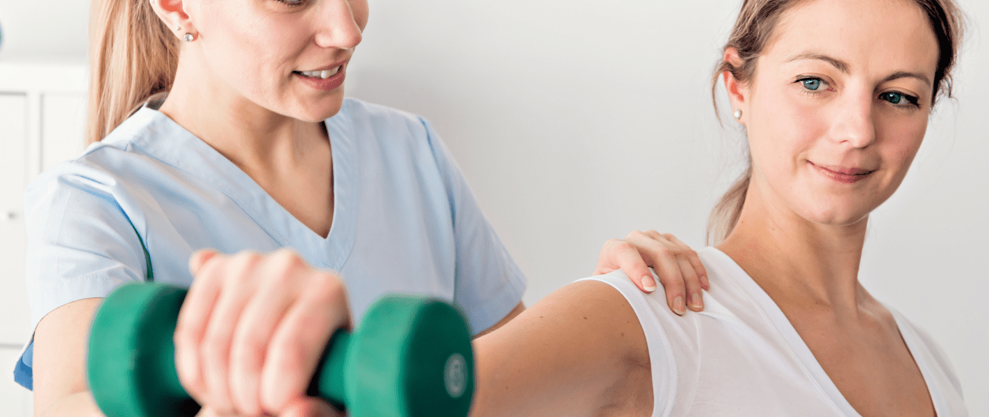 Physiotherapeutin hilft einer Patientin mit einem Hanteltraining in einer hellen, modernen Praxis.