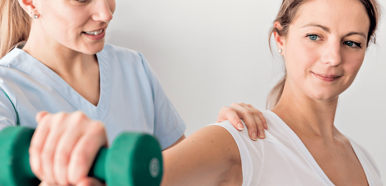 Physiotherapeutin hilft einer Patientin mit einem Hanteltraining in einer hellen, modernen Praxis.